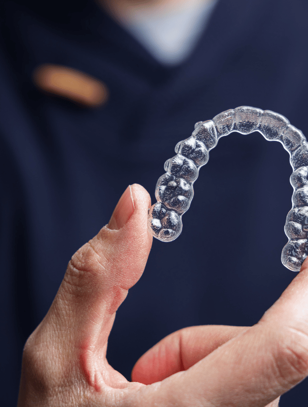 Dentist Holding Invisible Braces (Clear Aligners) - kohe Dental