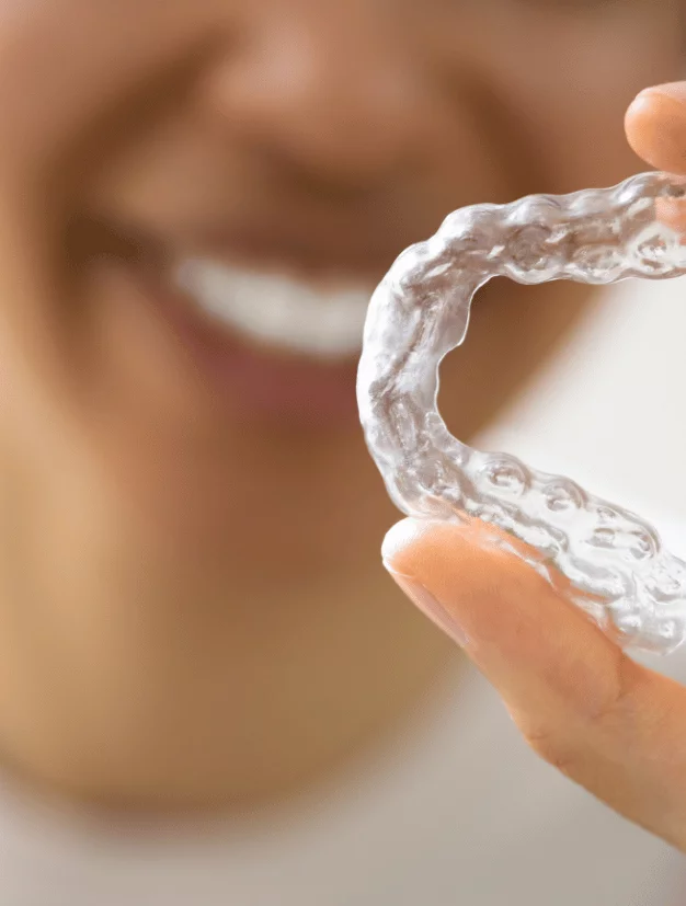 Woman Holding Invisible Braces (Clear Aligners) Between Her Fingers - kohe Dental