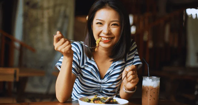 Woman Enjoying Her Food And Smiling - kohe Dental